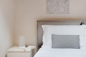 a white bed with a black and white pillow on it at Apartments Trieste Centro I 2 in Trieste