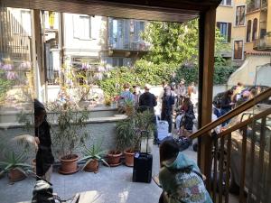 eine Gruppe von Menschen, die in einem Innenhof mit Pflanzen stehen in der Unterkunft Koala Hostel in Mailand