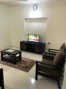a living room with a chair and a tv at Athrakkattu Enclave 6 Bedroom Luxury Apartment in Trivandrum