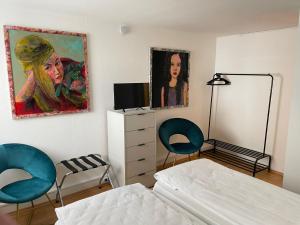 una camera da letto con due sedie e un dipinto sul muro di Appartamenti Quattro Ducati a Göppingen