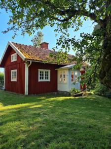 una casa roja y blanca con un patio de césped en Trevligt Torp i vacker natur, en Mellerud