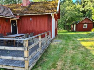 a red house with a wooden deck next to a building at Trevligt Torp i vacker natur in Mellerud +1 photo