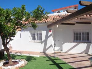 una casa blanca con un árbol en el patio en Villa MyRuedo, en Fuengirola