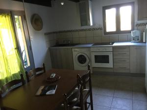 een keuken met een tafel en een wasmachine bij Appartements bord de mer - Accès privé à la plage in Prunete