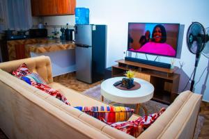 een woonkamer met een bank en een flatscreen-tv bij Cambric Luxe Studio Apartment in Kilifi