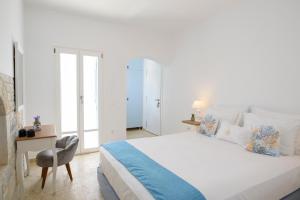 Tholariani Villas في أمورجوس: غرفة نوم بيضاء مع سرير ومكتب
