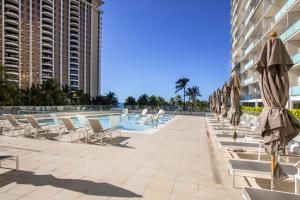 a swimming pool with lounge chairs and umbrellas at Ocean Front Amazing One bedroom condo in Honolulu