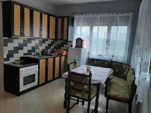 una pequeña cocina con mesa y una cocina con fregadero en Guesthouse Lula 2, en Tepelenë