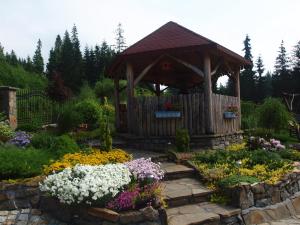 a wooden gazebo in a garden with flowers at Agroturystyka Pod Danielkami in Danielky