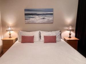 a bedroom with a large white bed with two lamps at Relaxing Turtle Bay townhome near the beach in Kahuku