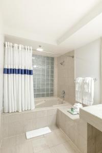 Atheneum Suite Hotel في ديترويت: حمام أبيض مع حوض استحمام ودش