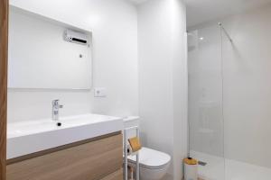 a white bathroom with a sink and a toilet at Apartamentos Rotilio in Sanxenxo