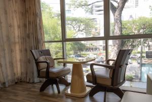 Cozy Gurney Georgetown Private Apartment Penang في جورج تاون: كرسيين وطاولة أمام النافذة