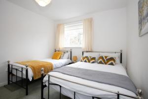 two beds in a small room with a window at Hurley House in Cheadle Hulme