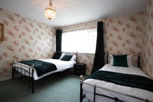 a bedroom with two beds and a window at Hurley House in Cheadle Hulme
