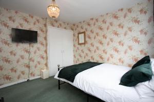 a bedroom with a bed and a tv on the wall at Hurley House in Cheadle Hulme