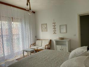 a bedroom with a bed and a chair and a window at CASE DEL MAR nel centro storico in Santa Teresa Gallura