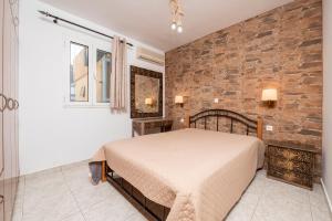 a bedroom with a bed and a brick wall at Villa Giorgos in Kefalos