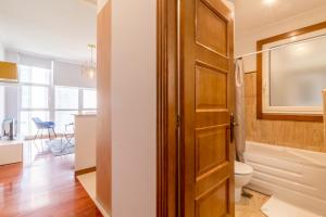 a bathroom with a toilet and a wooden door at Principe Premium Loft Vigo in Vigo