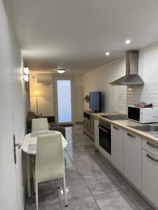 a kitchen with white cabinets and a table with chairs at Maureillas - appartement 2 personnes - classé in Maureillas