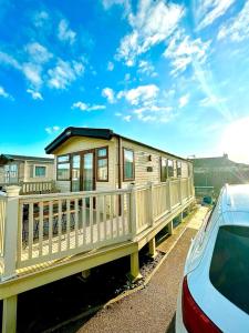 a house with a balcony and a car parked next to it at Seascape Camber Sands in Camber