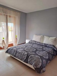 a bedroom with a bed with a blue blanket and a window at La Sosta House Anzio in Anzio