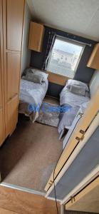 two beds in a small room with a window at Whitehouse Leisure Park North wales 6 birth caravan in Kinmel Bay