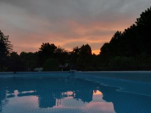 an empty swimming pool with a sunset in the background at B&B Da Leone in Palazzolo dello Stella