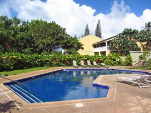 a swimming pool with chairs and a house at Spacious Townhouse by the beach in Kahuku