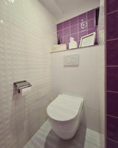 a white toilet in a bathroom with purple tiles at Kieler Eiderparadies in Flintbek