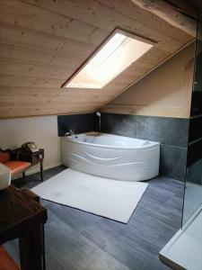 een badkamer met een bad en een dakraam bij La Basse Aubin in Épinal