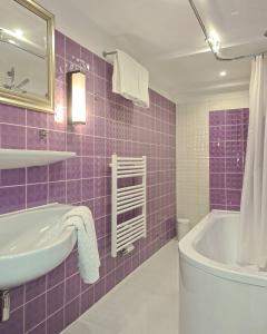 a purple tiled bathroom with a sink and a tub at Kieler Eiderparadies in Flintbek