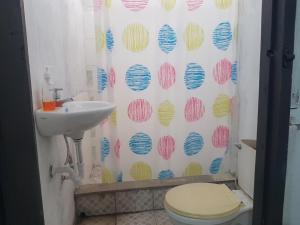 a bathroom with a sink and a toilet and a shower curtain at Lulu Mocktails in San Juan del Sur