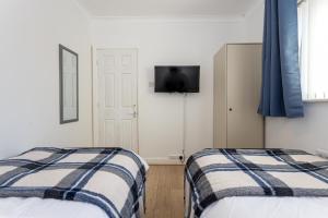 two beds in a room with a tv on the wall at Renfrew House in Bolton