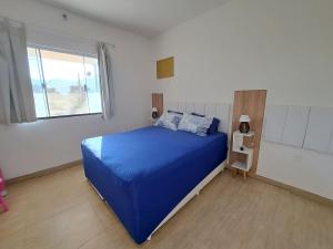 um quarto com uma cama azul e uma janela em Casa de campo Ar piscina Churrasqueira Saquarema em Jaconé
