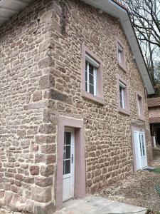 een bakstenen gebouw met een witte deur en ramen bij La Basse Aubin in Épinal