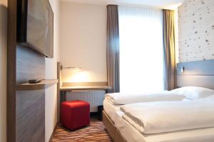 a hotel room with two beds and a television at Amaro Hotel in Bergkirchen