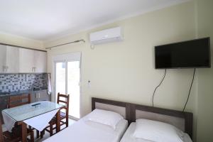 a bedroom with a bed and a table and a tv on the wall at Casa Blanca Rooms in Himare