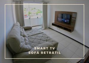 uma sala de estar com um sofá e uma televisão de ecrã plano em TH 3102 - Flat de 2 quartos com varanda em Governador Valadares