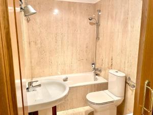 a bathroom with a toilet and a sink and a tub at APARTAMENTO CARMEN in Gijón