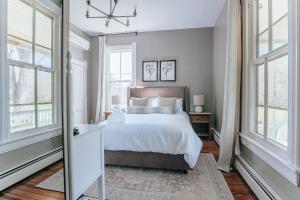 a bedroom with a bed with white sheets and windows at Afton Mountain Inn in Afton