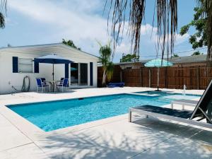a swimming pool with a table and an umbrella at Little Beach House w/ POOL&SPA - 5 minutes to Vanderbilt Beach (Pet Friendly) in Naples