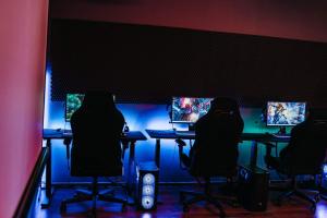 a room with a table with four chairs and computer screens at Gaming House Kraków in Kraków