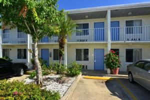 ein Gebäude mit blauen Türen und Bäumen auf einem Parkplatz in der Unterkunft Americas Best Value Inn Bradenton-Sarasota in Bradenton