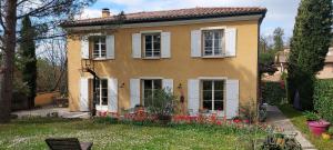 a yellow house with white windows and red flowers at Chambre d'hôte chez Florence in Vourles
