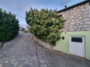 a stone building with a white door and a tree at Atelier apartment in Krasica