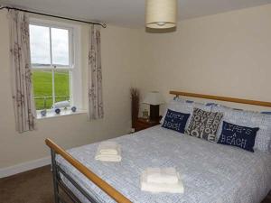 a bedroom with a bed with blue pillows and a window at Gulls Hatch in Maryport