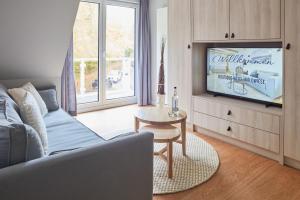 a living room with a couch and a tv at Boutique Hotel Waldwiese in Hohwacht