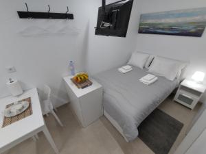 a white bedroom with a bed and a table with fruit on it at Room Dream Beato in Lisbon