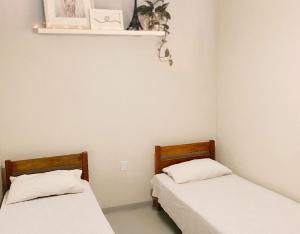 two beds in a small room with white sheets at Pousada do beco in Caravelas